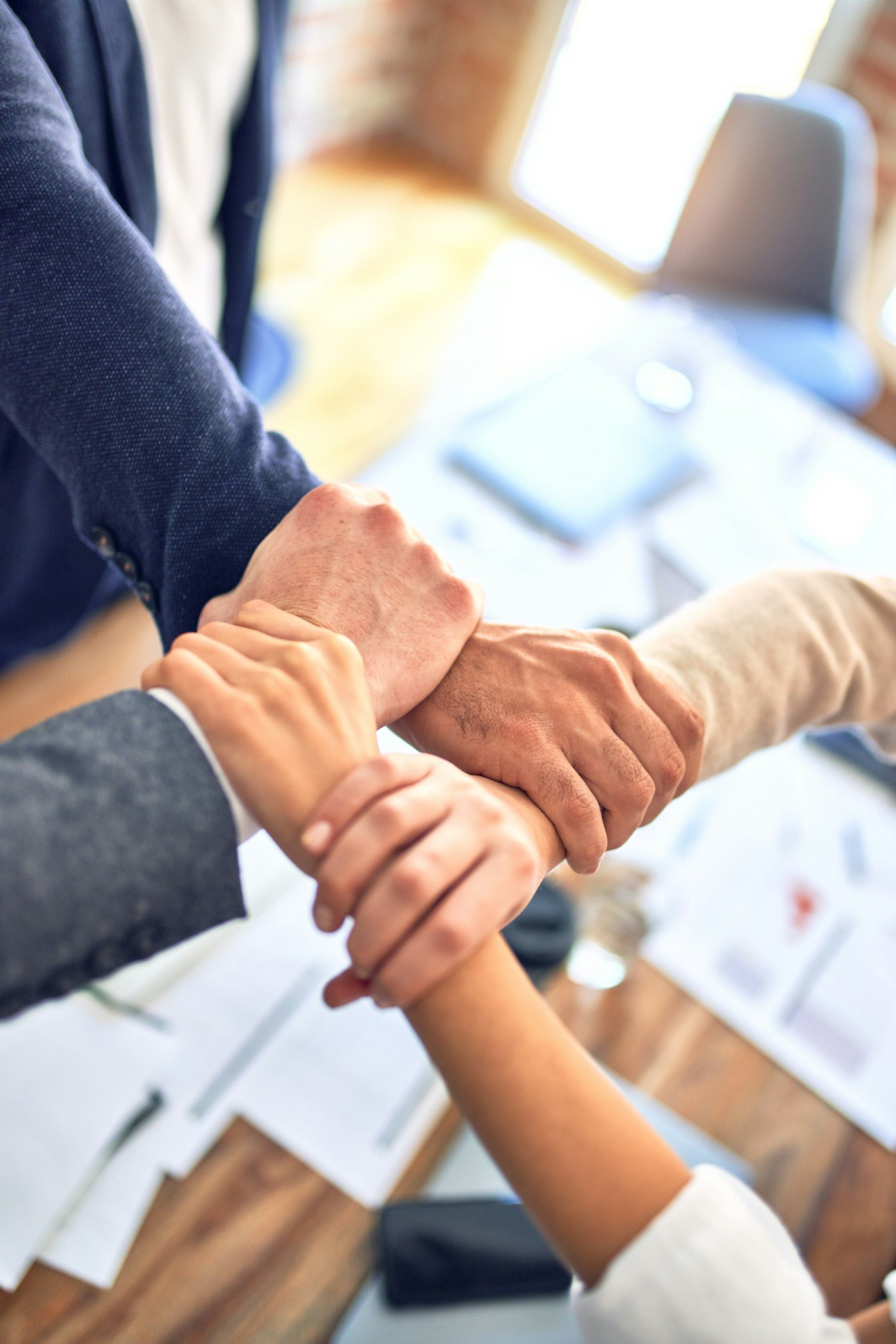 Four colleagues gripping each other's wrists in an interlocking display of teamwork