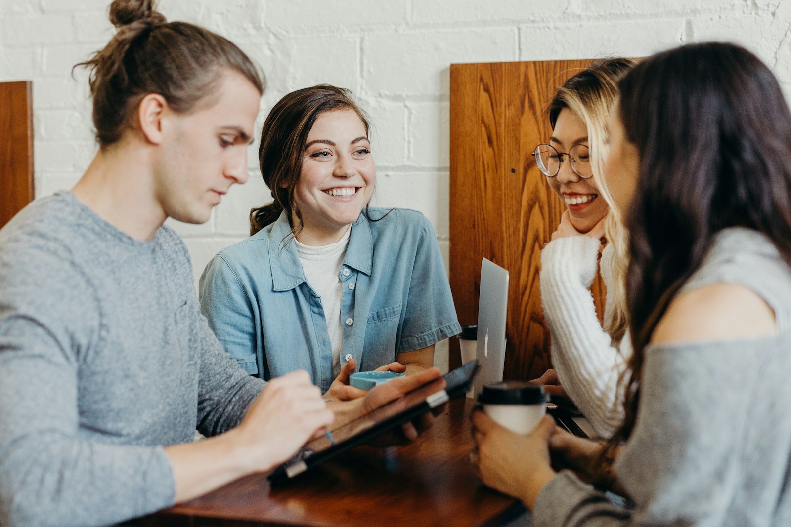 A small team of support workers talking and smiling together around a table in warm natural light
